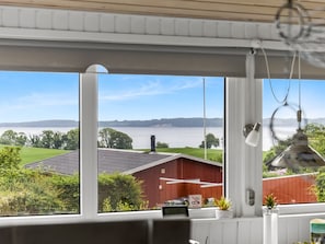 A room with a large window offering a view of a red barn and a body of water. - "Agla" - 350m from the sea by Interhome (Aabenraa)