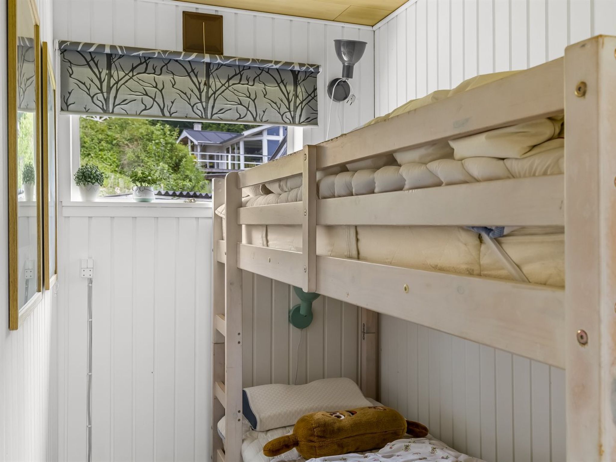Una cama litera con ventana y vista a una casa.
