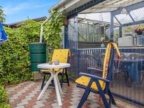 A covered patio area with a table and chairs, a green barrel, and a blue fence. - "Agla" - 350m from the sea by Interhome (Aabenraa)