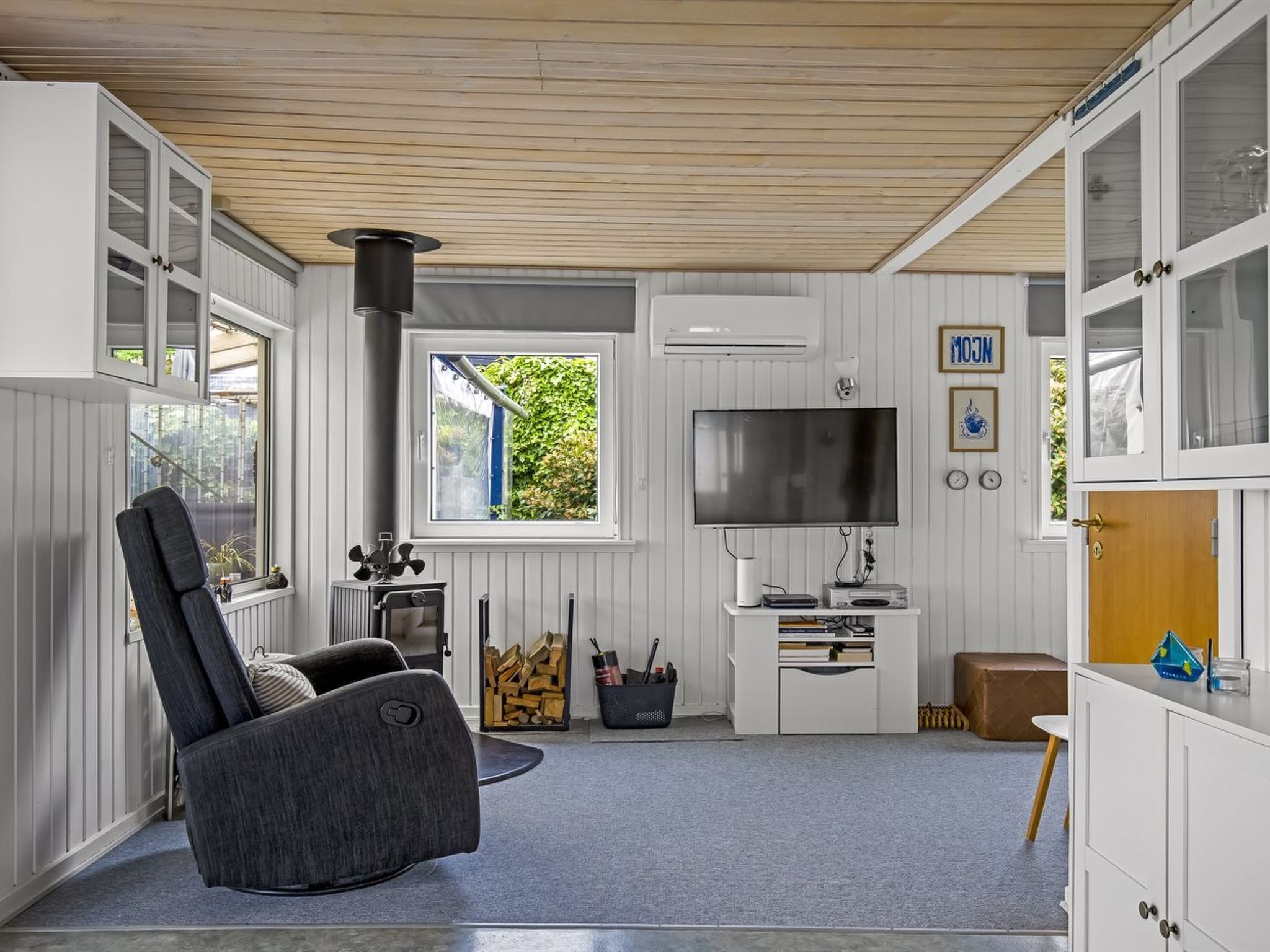 Ein gemütliches Wohnzimmer mit Kamin, einem bequemen Sessel, einem Fernseher und einem kleinen Tisch mit verschiedenen Gegenständen.