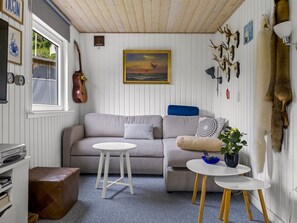 A cozy living room with a sofa, two small tables, a guitar, and various wall decorations including a painting and animal skulls. - "Agla" - 350m from the sea by Interhome (Aabenraa)
