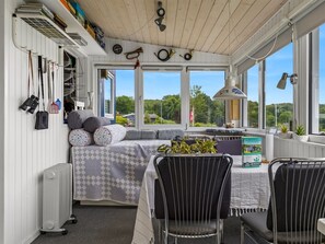 Una habitación acogedora con una cama, una mesa con sillas, un radiador y un amplio ventanal con vista a la vegetación.