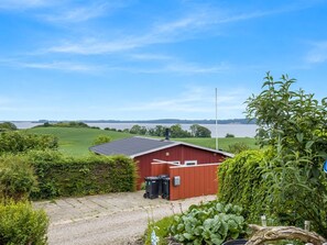 A red building with a sloped roof, a gravel driveway, and a view of a large body of water. - "Agla" - 350m from the sea by Interhome (Aabenraa)