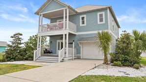 Ein zweistöckiges Haus mit Balkon, Garage und Veranda.