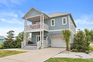 Ein zweistöckiges Haus mit Balkon, Garage und Veranda.