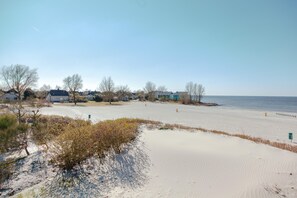 Une plage de sable avec des maisons en arrière-plan et un ciel dégagé.