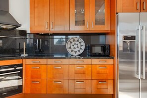 A kitchen with wooden cabinets, a microwave, and a stainless steel refrigerator. - Luxury Makkum Beachvilla for 6 (Makkum)