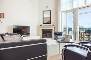 Un salon moderne doté d’un téléviseur à écran plat, d’une cheminée, d’un canapé et d’un coin repas avec des chaises.