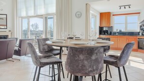A modern kitchen with a dining area, large windows, and a view of the outdoors. - Luxury Makkum Beachvilla for 6 (Makkum)