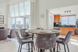 A modern kitchen with a dining area, large windows, and a view of the outdoors. - Luxury Makkum Beachvilla for 6 (Makkum)