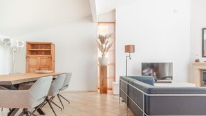 A modern living space with a dining area, a sofa, a TV, and a decorative plant. - Luxury Makkum Beachvilla for 6 (Makkum)