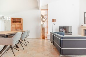 A modern living space with a dining area, a sofa, a TV, and a decorative plant. - Luxury Makkum Beachvilla for 6 (Makkum)