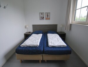 A double bed with a headboard, two bedside tables with lamps, and two framed pictures on the wall. - Classic Beach Villa With Whirlpool (Makkum)