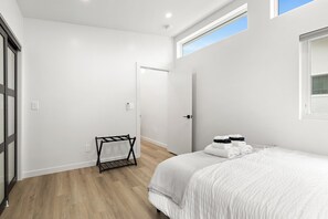 A modern bedroom with a bed, a small seating area, and a door leading to another room. - Spacious w/1BR 1Bath - Near DTLA (Los Angeles)