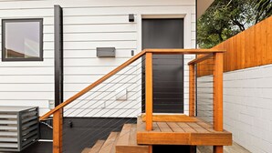 A wooden staircase with a metal railing leading to a black door. - Spacious w/1BR 1Bath - Near DTLA (Los Angeles)