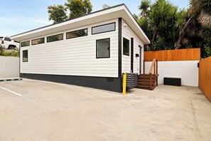 A modern single-story mobile home with a flat roof, large windows, and a concrete driveway. - Spacious w/1BR 1Bath - Near DTLA (Los Angeles)