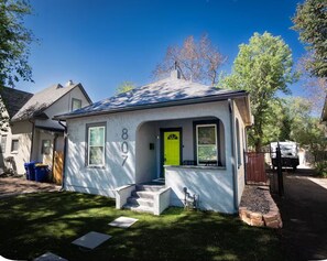 A single-story house with a bright green door, numbered 807, and a small front porch with steps leading to the entrance. - Downtown CO Springs 1BR Cottage with Sunroom (Colorado Springs)