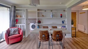 A modern kitchen with a dining area, a red sofa, and a large window with curtains. - Lochside Perthshire Lodge for 4 (Auchterarder)