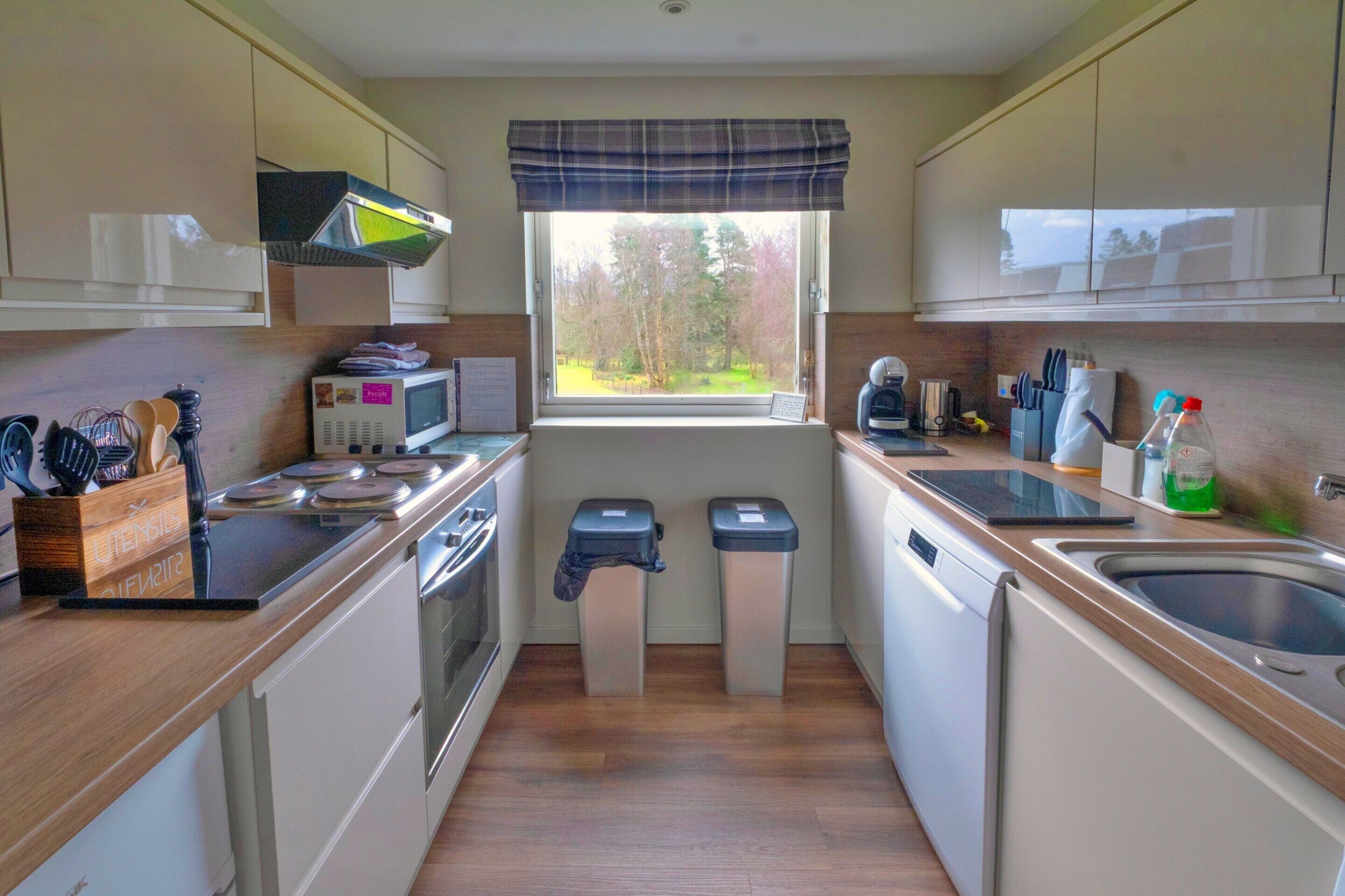 A compact kitchen with a window, microwave, stove, and sink.