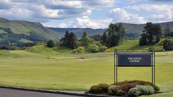 A sign for The King's Course, a golf course with a view of rolling hills and trees.