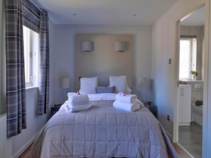 A hotel room with a large bed, two bedside lamps, a window with curtains, and a view of the bathroom. - Lochside Perthshire Lodge for 4 (Auchterarder)