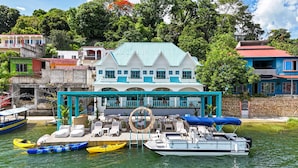 A waterfront property with a large house, a covered outdoor seating area, and several boats. - Casa Astral  (Flores)