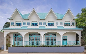 A two-story building with a white facade, blue trim, and a green roof. - Casa Astral  (Flores)