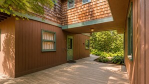Une maison en bois avec un porche couvert et une porte verte.
