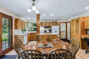 A spacious kitchen with wooden cabinets, a central island, and a dining area with a wooden table and chairs. - Spacious Upstairs Apartment Near Stowe Mountain (Stowe)