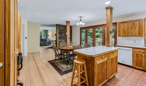 A spacious kitchen with wooden cabinets, a central island, and a dining area with chairs. - Spacious Upstairs Apartment Near Stowe Mountain (Stowe)