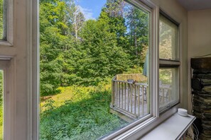 Une pièce dotée d’une grande fenêtre donnant sur un jardin luxuriant et d’une terrasse en bois.