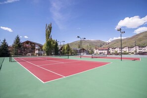 Ein Tennisplatz mit Netz, umgeben von Gebäuden und Bäumen.