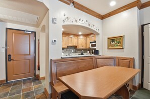 A room with a wooden bench, a door, and a kitchen area with wooden cabinets and a tiled backsplash. - Villa 2080 1 Bed 1 Bath Full Kitchen in the heart of Midway Utah (Midway)