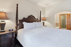 Een hotelkamer met een hemelbed, een nachtkastje met een lamp en een houten deur.