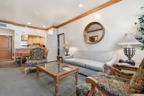 A living room with a sofa, armchairs, a coffee table, and a dining area with wooden cabinets and a kitchen in the background. - Villa 2080 1 Bed 1 Bath Full Kitchen in the heart of Midway Utah (Midway)