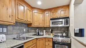 A kitchen with wooden cabinets, a stainless steel microwave, a gas stove, and a dishwasher. - Villa 2080 1 Bed 1 Bath Full Kitchen in the heart of Midway Utah (Midway)