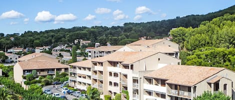 Zona residencial con edificios de varios pisos, un estacionamiento y abundante vegetación.