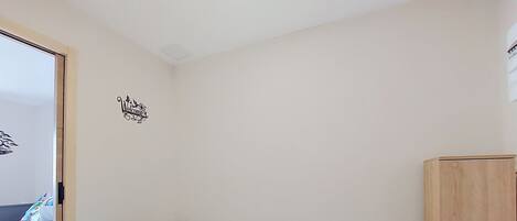 Un dormitorio con cama, armario de madera y decoración en la pared.