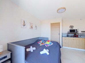 A modern hotel room with a bed, a small kitchenette, and artwork on the walls. - Les Aigues Marines by Interhome (Saint Cyr sur Mer La Madrague)