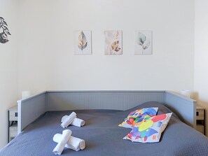 Ein Schlafzimmer mit einem Bett, zwei Kissen, einem Kopfteil und drei an der Wand befestigten Kunstwerken.