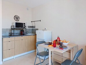 A compact kitchen with a microwave, a small refrigerator, and a dining table set with chairs. - Les Aigues Marines by Interhome (Saint Cyr sur Mer La Madrague)