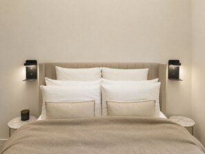Ein Bett mit beigem Kopfteil, zwei Nachttische und Wandleuchten.