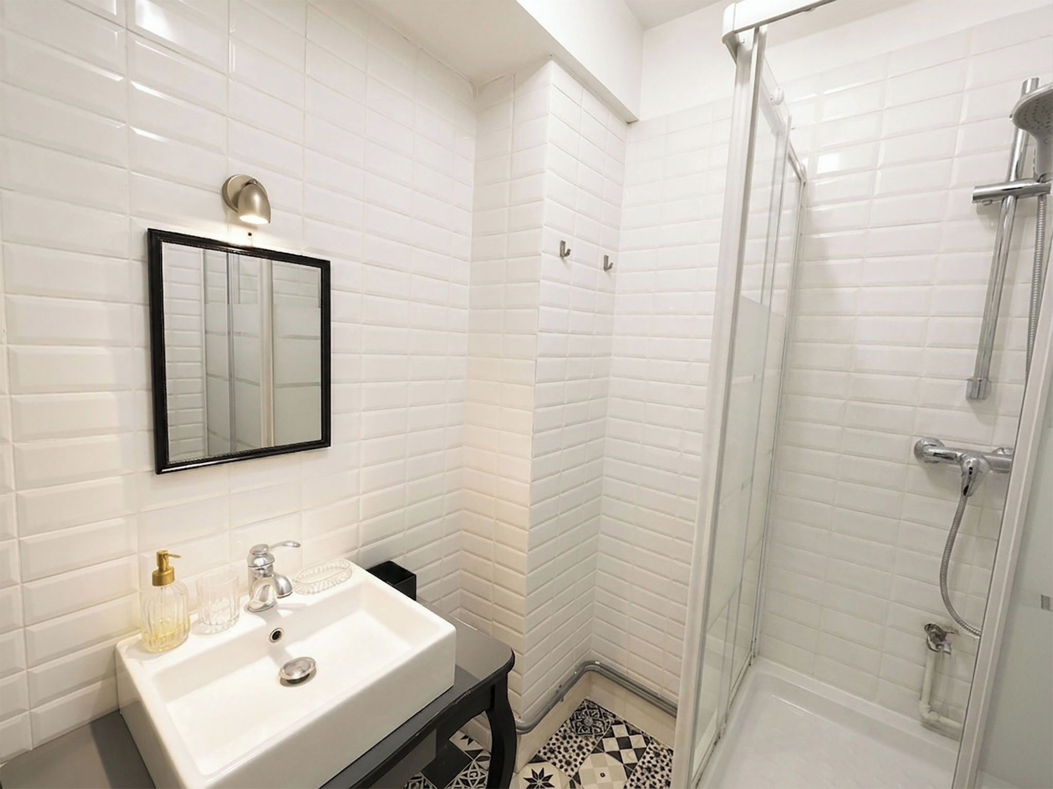 A bathroom with a white sink, a mirror, and a shower.