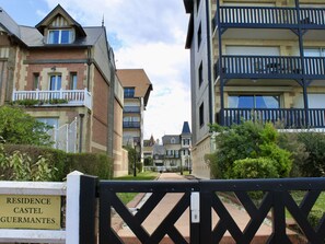 Een omheind toegangshek naar een woongebied, met een bord waarop 'Residence Castel Guermantes' staat.
