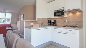 A compact kitchen with white cabinets, a microwave, a gas stove, and a coffee maker. - Scharendijke Stay With Private Sauna (Scharendijke)