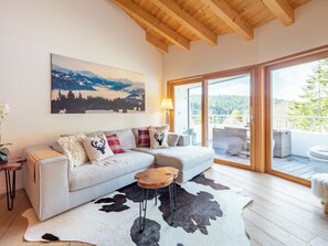 Ein modernes Wohnzimmer mit einer Couch, einem aufgehängten Gemälde, einem Holztisch und einem Kuhfellteppich.