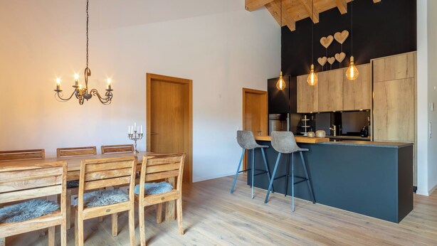 Eine moderne Küche mit Holzausstattung, einer Bar und einem Essbereich mit Holztisch und -stühlen.