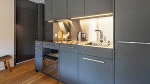 Eine moderne Küche mit grauen Schränken, einer Edelstahlspüle und einem eingebauten Backofen.