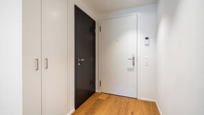 Ein Flur mit Holzboden, einer schwarzen Tür und einer weißen Tür mit Bedienfeld.