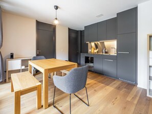 Uma cozinha moderna com armários escuros, uma mesa de jantar de madeira e um banco.